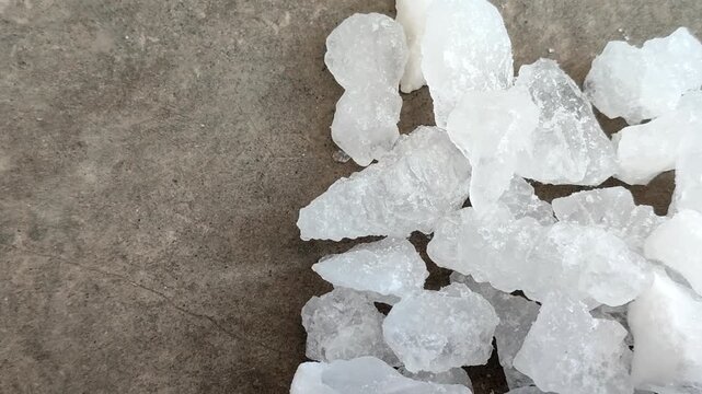 Natural white alum crystal stones on a textured concrete surface. Ideal for natural deodorant, body care, cosmetics, and water purification concepts