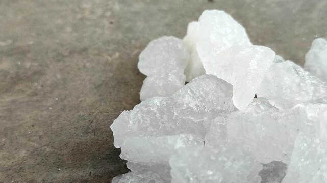 Natural white alum crystal stones on a textured concrete surface. Ideal for natural deodorant, body care, cosmetics, and water purification concepts