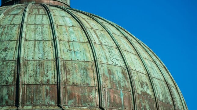 Old weathered copper dome roof against a clear blue sky