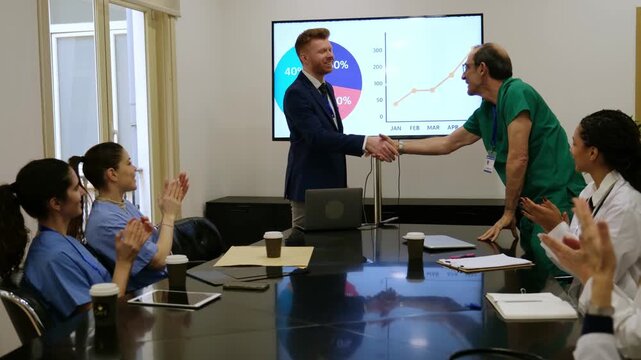 Medical team applauding a businessman after a presentation and shaking hands in the meeting room