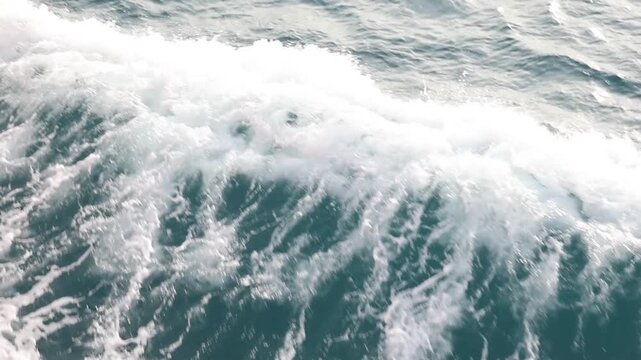 Full frame slow motion drone video of rough ocean surface texture with swirling whitewash patterns aerial view of and ocean with waves

