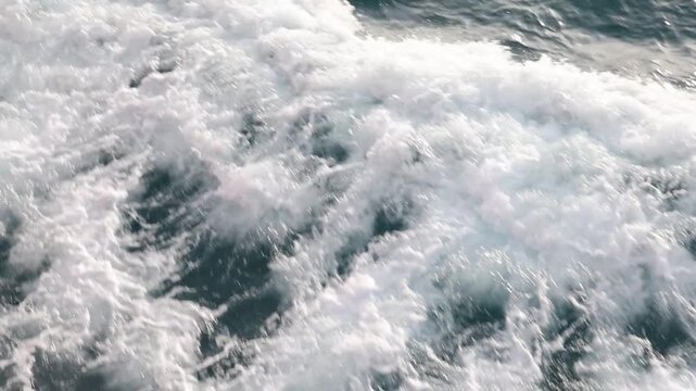 Full frame slow motion drone video of rough ocean surface texture with swirling whitewash patterns aerial view of and ocean with waves

