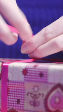 Decorating gift wrapped present with red ribbon
