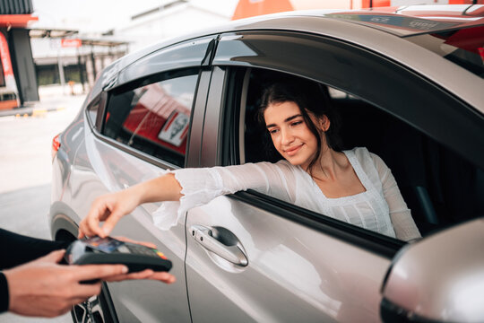 Woman making a contactless payment with a credit card terminal from her car at a gas station