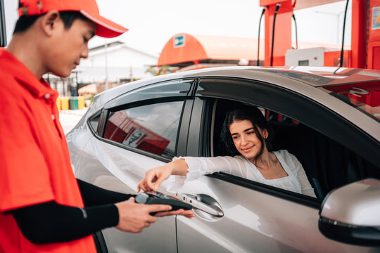 Woman making a contactless payment with a credit card terminal from her car at a gas station