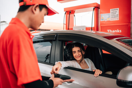 Woman making a contactless payment with a credit card terminal from her car at a gas station