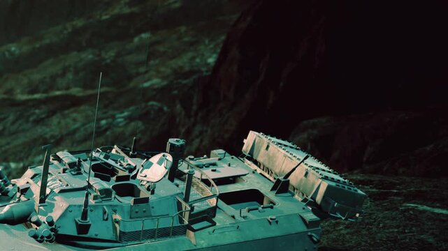 A military tank sits on rocky ground next to a steep slope. The sun shines down, highlighting the details of the tank. The landscape around is rugged and natural.