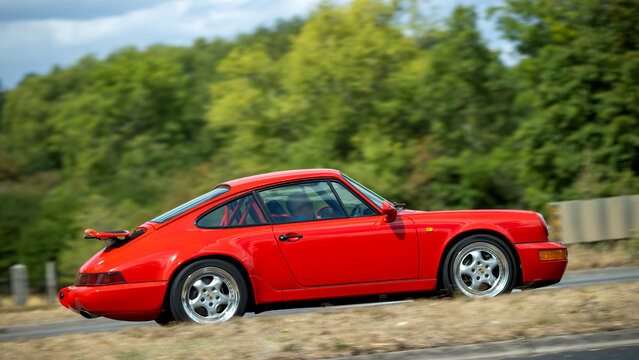 Milton Keynes,UK - Aug 22nd 2026: 1989 red Porsche 911 classic car driving on a British road