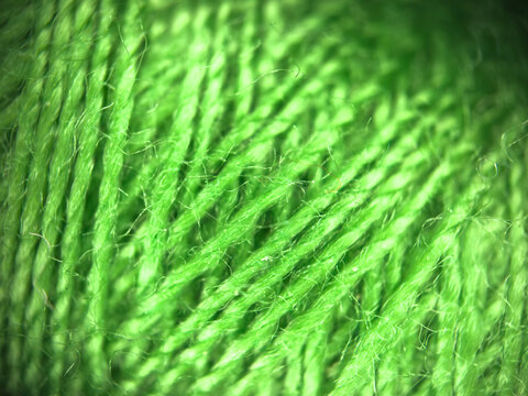 Green yarn thread texture close up macro concept for knitting, textile industry, handicraft hobby, wool material background, eco friendly fabric, needlework, and bright green wallpaper design. High qu