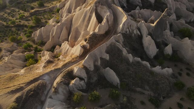 Cinematic aerial drone footage of Cappadocia&rsquo;s spectacular rock formations and fairy chimneys at sunset, bathed in warm golden light, showcasing the unique volcanic landscape of central Turkey.