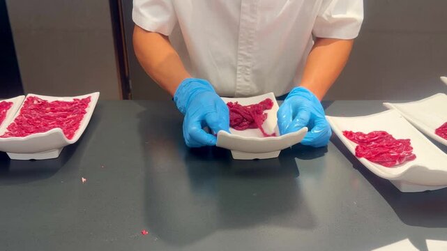 Chef Hands Thinly Slicing Marbled Beef and Plating for Hot Pot &ndash; Preparing Premium Meat 