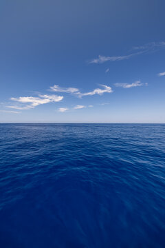 Serene deep blue sea calm open water wide bright horizon minimal summer sky ocean surface vertical view. Peaceful summer nature seascape meditation wellbeing. Relaxing inspiring coastal wallpaper scen