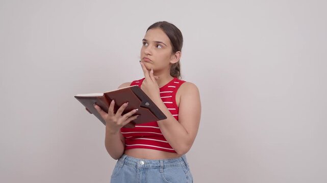 Indian Teenage Girl Reading from Notebook and Thinking