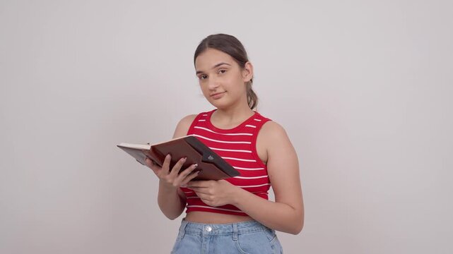 Indian Teenage Girl Reading from Notebook and Smiling at Camera