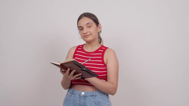 Indian Teenage Girl Writing in Notebook and Smiling at Camera