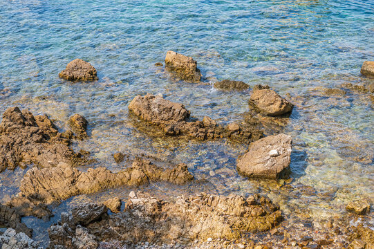 Rocky Mediterranean coastline with clear turquoise water and sunlit shallows
