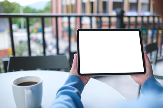 Mockup image of a woman holding digital tablet with blank white desktop screen in cafe