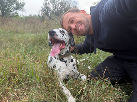 Happy Man Taking Selfie With Dalmatian Dog Outdoors In Countryside Field