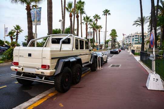 Cannes, France - August 02, 2026: A beige Mercedes-Benz G63 AMG 6x6 is parked on a street lined with palm trees and luxury cars