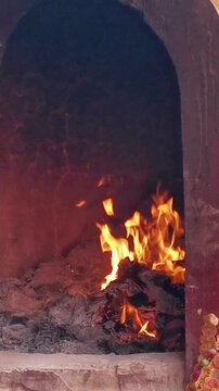 A traditional Chinese joss paper burner furnace with bright flames burning ceremonial paper offerings outside a temple during a religious ritual celebration