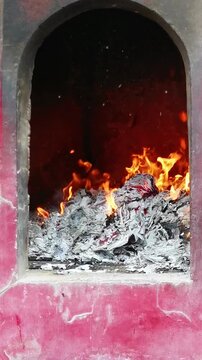 Traditional Chinese temple incense furnace with glowing flames, burning joss paper and ashes, symbolizing worship, ancestral offerings, spirituality and cultural religious traditions