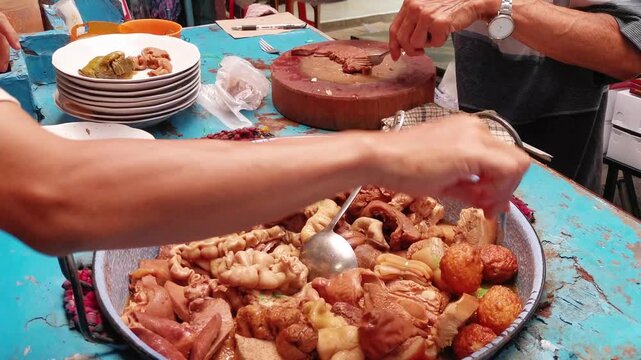 Street food vendor preparing Cu-Nyuk Siomay (Pork Dumplings) dish on blue table