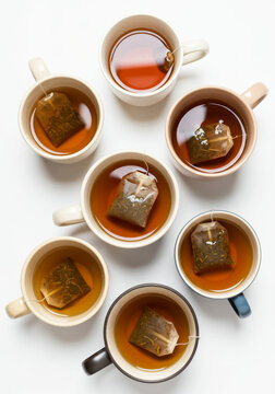 Assorted Tea Cups with Steeping Tea Bags on White Background
