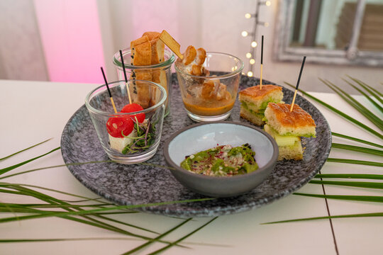 Vorspeisenplatte (Ap&eacute;ro-Platte) mit verschiedenen Komponenten: Focaccia-Schnittchen, Dip (Guacamole oder Pesto), kleine Gl&auml;ser mit Tomate-Mozzarella-Spiessen, Grissini/Brotstangen und Fleisch