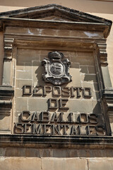 Historic horse stud depot inscription with crowned heraldic emblem and stone architectural frame in Baeza, Andalusia, Spain © Goodwoon Mallorca