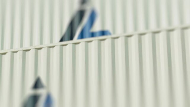 Slow panning shot revealing stacks of weathered and rusty intermodal cargo containers at a harbor