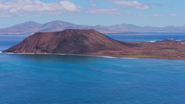 Areal views of Lobos Island, a small, uninhabited volcanic nature reserve with crescent-shaped white sand beach with crystal-clear turquoise waters located in Fuerteventura, Canary Islands, Spain.