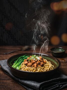 Mie Ayam. Mie Ayam kecap bakmi. Indonesian Chicken Noodle Soup. Mie Ayam Dark Moody Smoke. Classic Indonesian Chicken Noodle Soup Served in Ceramic Bowl on Dark Wooden Table with Visible Steam Smoke.
