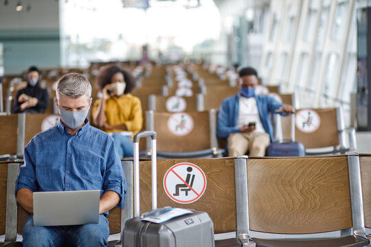 Travelers maintain physical distance while waiting for flights, adhering to safety protocols with masks and designated seating