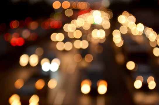 A background of beautiful, out-of-focus vehicle lights on a city street, set against the darkness of night traffic.