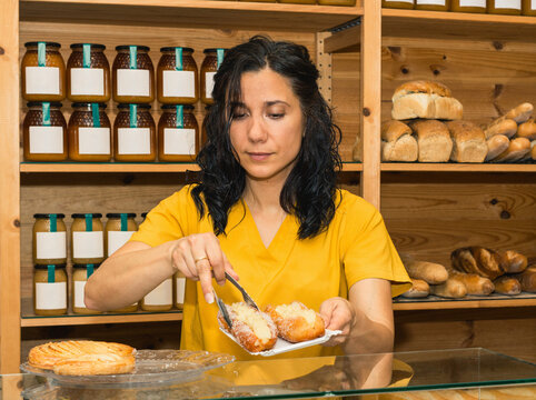 Woman serving fresh pastry in bakery shop