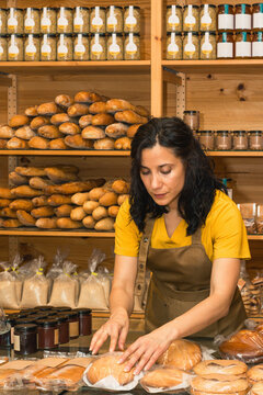 Woman working in a bakery arranging artisanal cakes.