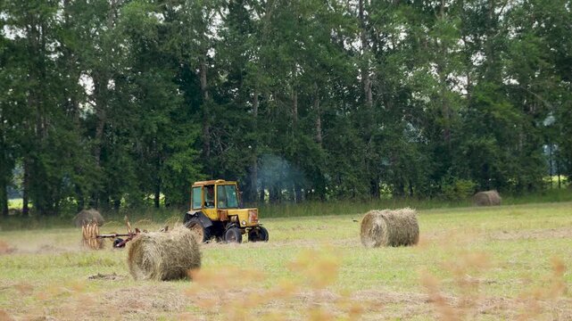 Yellow Vintage Tractor Tedding Hay Near Straw Bales
