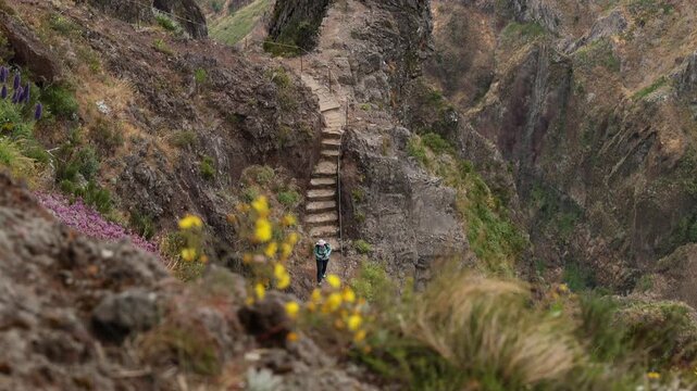 Madeira, Portugal - July 13, 2026: Hiker walking along the narrow stone staircase on the rugged mountain trail between Pico do Arieiro and Pico Ruivo. 4K video.