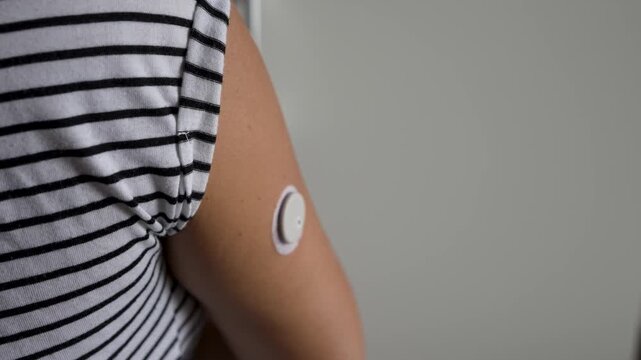 Close-up of a woman applying a continuous glucose monitoring (CGM) sensor to her arm using an applicator for diabetes control