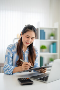 Young asian woman review paper documents, managing business affairs, summarizing taxes, planning future investments, accounting at home office.
