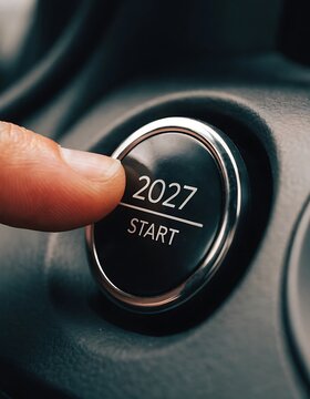 Close up of a human finger pressing a start button featuring the year 2027 concept