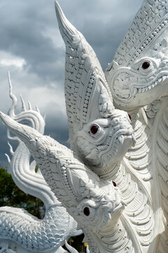 Intricate white multi-headed serpent sculpture against a dramatic cloudy sky