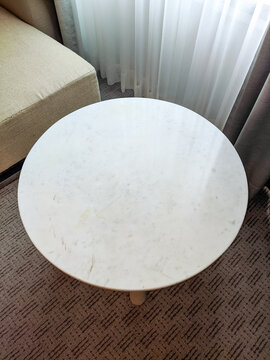 Minimalist small wooden table in a simple interior, featuring a round tabletop, clean lines, and neutral tones that create a warm and understated furniture composition.