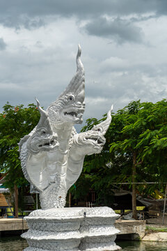 Intricate three-headed serpent statue guards a tranquil waterside setting