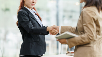 Businesswomen shaking hands in a corporate office, symbolizing agreement, partnership, success, deal, cooperation, and professional collaboration during a meeting © David