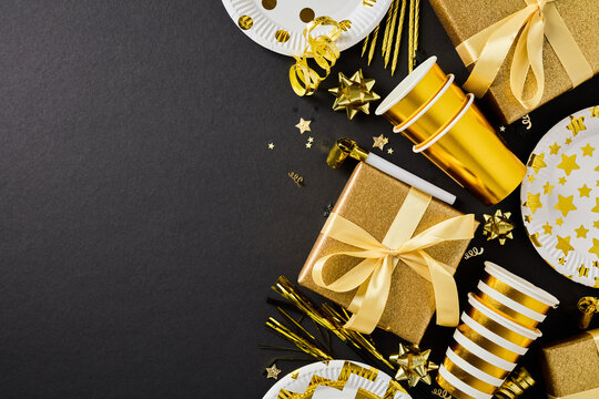 Golden party supplies side border on dark black background flatlay