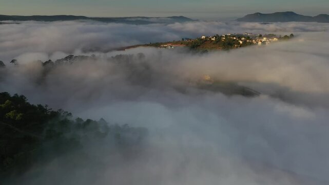 Aerial sunrise over Trai Mat, Xuan Truong Ward, Da Lat, Lam Dong, Vietnam, with drifting mist, clouds and golden sunlight illuminating the peaceful highland landscape.