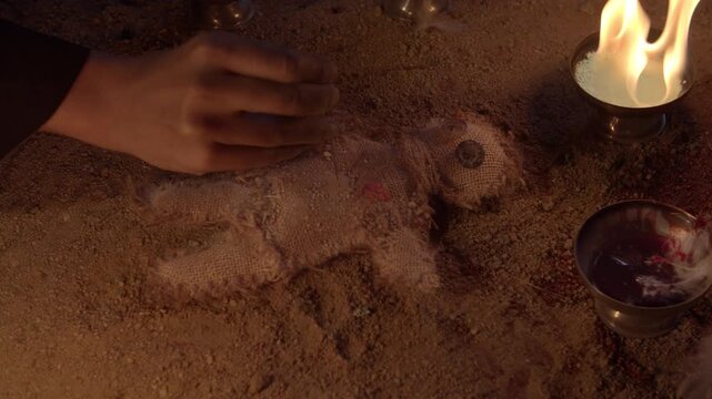 A woman&acute;s hand stabs a voodoo doll, then the doll starts to bleed