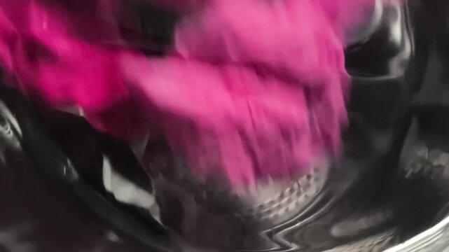 Colorful laundry items being agitated in a washing machine drum, showcasing the swirling motion of fabrics and water during the washing process
