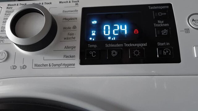Washing machine control panel displaying countdown timer and settings for drying cycle, with visible buttons and indicators in a modern laundry room setting